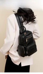 Rear view of model wearing a black PU leather backpack with gold hardware and multi-pockets