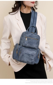 Detail view of retro blue denim crossbody bag with multiple zippers and bronze hardware