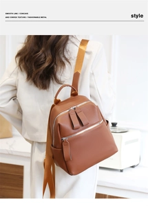 Detailed view of brown pebbled leather backpack on model with silver zippers