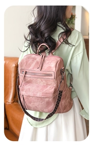 Detail of dusty pink PU leather backpack with vintage texture and woven strap on model