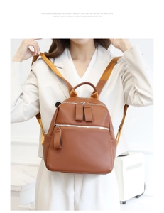 Detailed shot of brown lychee-patterned PU leather backpack on female model in white blazer