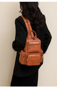 Detailed back view of vintage brown leather backpack with multiple zip pockets