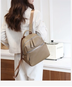 Detail of khaki pebbled leather backpack showing metal zippers and soft PU texture