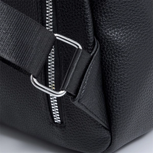 Détail d'un sac à dos en cuir grainé noir avec boucle métallique et sangle tressée