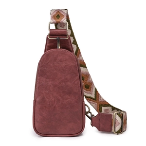 Detail of vintage burgundy leather chest bag featuring ethnic pattern woven strap