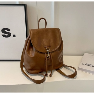 Detail of vintage brown textured leather backpack with silver metal hook and drawstring closure