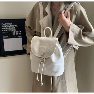 Close-up of white lychee leather backpack with drawstring closure and golden metal hook detail