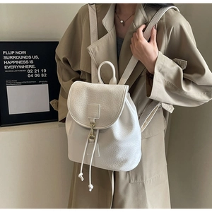 Detailed close-up of a white lychee-textured leather backpack with gold metal hook closure