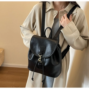 Close-up of black litchi pattern PU leather backpack with gold metal hook lock and drawstring
