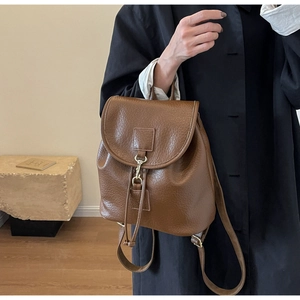 Close-up of brown vintage PU leather backpack with lychee texture and metal hook