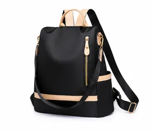 Detail of black nylon anti-theft backpack with beige accents and gold hardware