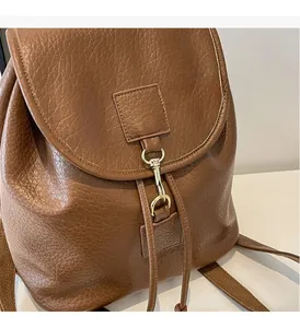 Detail of vintage brown PU leather backpack featuring lychee texture and gold metal hook