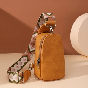 Detail of ginger leather chest bag showing textured finish and vintage woven strap