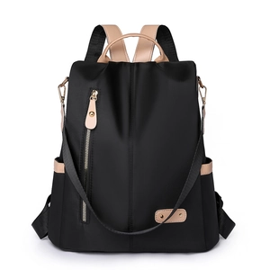 Minimalist black nylon backpack with brown leather trim and golden zipper details