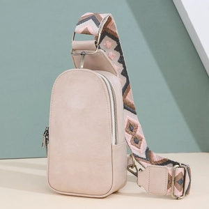 Detail of cream leather chest bag with a geometric woven strap and gold metal zipper