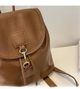 Detail of brown litchi pattern leather backpack with gold buckle and drawstring closure