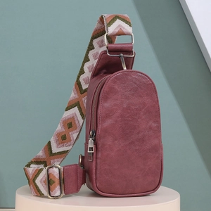 Close-up of reddish brown leather chest bag with decorative ethnic jacquard strap