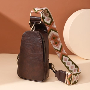 Detail of vintage brown textured chest bag featuring a colorful geometric woven strap