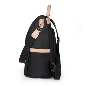 Side view of black nylon backpack with brown leather trim and golden metal D-rings