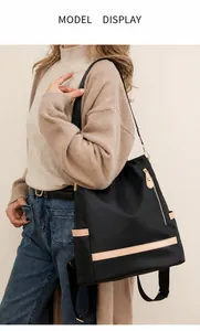 Detail of black nylon backpack featuring beige leather trim and golden metal zippers