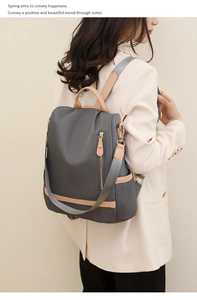 Close-up of dark grey nylon backpack with light brown faux leather accents and metal zippers