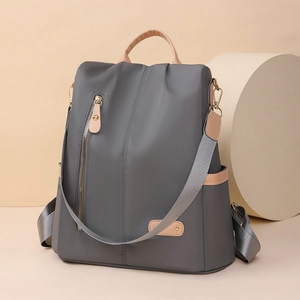 Detail of grey nylon backpack with side leather accents and functional vertical zip