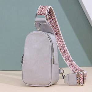 Close-up of gray PU leather sling bag with colorful geometric woven shoulder strap detail