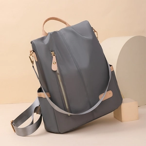 Detail view of water-resistant nylon backpack with elegant leather trim and gold zippers
