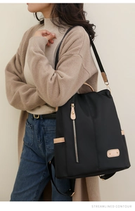 Close-up of black nylon backpack with brown leather details worn by a model