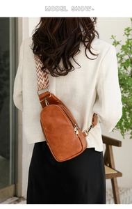 Brown leather sling bag for women with geometric pattern strap shown on model