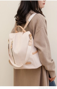 Detailed side view of beige nylon backpack with leather handles and streamlined contour