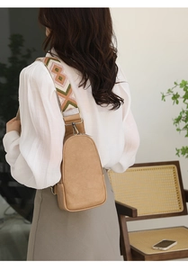 Detail of light camel PU leather crossbody bag with geometric knit strap on model