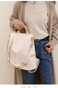 Close-up of beige nylon backpack with theft-proof design and brown leather details