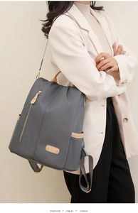 Practical dark grey nylon backpack with brown leather trim shown on model