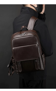 Détail du sac à dos en cuir marron foncé montrant le grain de peau et les boucles argentées