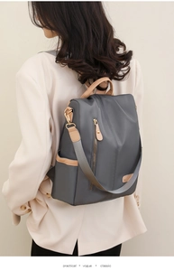 Detailed view of dark grey nylon backpack with leather pulls and back anti-theft zipper