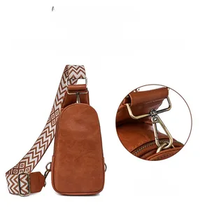 Detail view of brown vintage chest bag with textured leather and metal hook