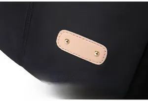 Detailed close-up of premium black nylon fabric with beige leather tag and gold rivets