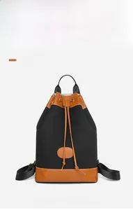 Detail of black oxford fabric backpack with brown leather trim and drawstring closure