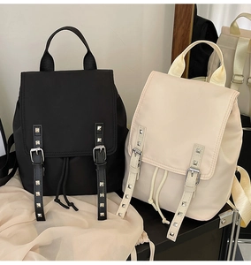 Detail view of large nylon backpack featuring rivet decor and flap drawstring closure