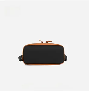Detail view of the rectangular oxford cloth bag bottom with brown leather piping and trim