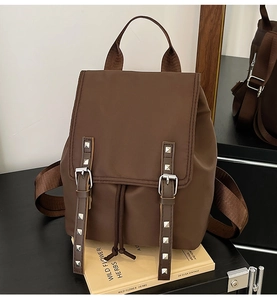 Detail of dark brown backpack featuring silver studs, buckle closure and drawstring design