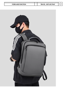 Profile view of grey waterproof business backpack with USB port on male model