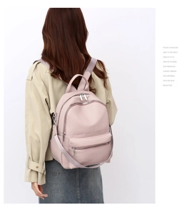 Close-up of pink PU leather backpack featuring litchi grain texture and dual zippers