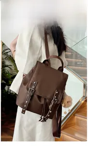 Fashionable dark brown backpack with silver rivet straps and plush bear charm on model
