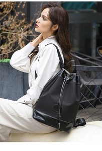 Detail of black nylon drawstring backpack with contrast white stitching and leather trim