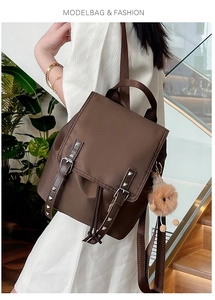 Detail of dark brown fashion backpack with leather straps and cute plush ball charm accessory