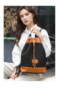Outdoor lifestyle shot of a black and brown oxford cloth drawstring bucket backpack