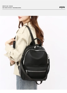 Detail of black pebbled PU leather backpack with silver zippers on female model