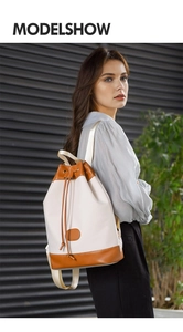 Detailed side view of cream oxford canvas backpack with brown leather trim on a model